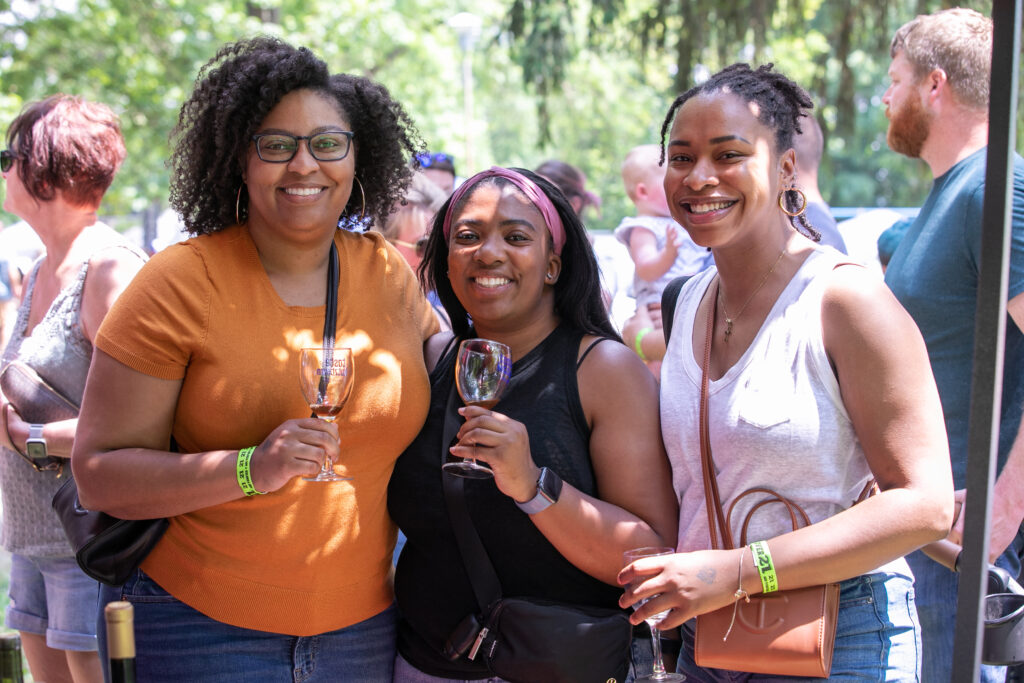 3 young women posing with wine glasses at an outdoor wine festival in PA