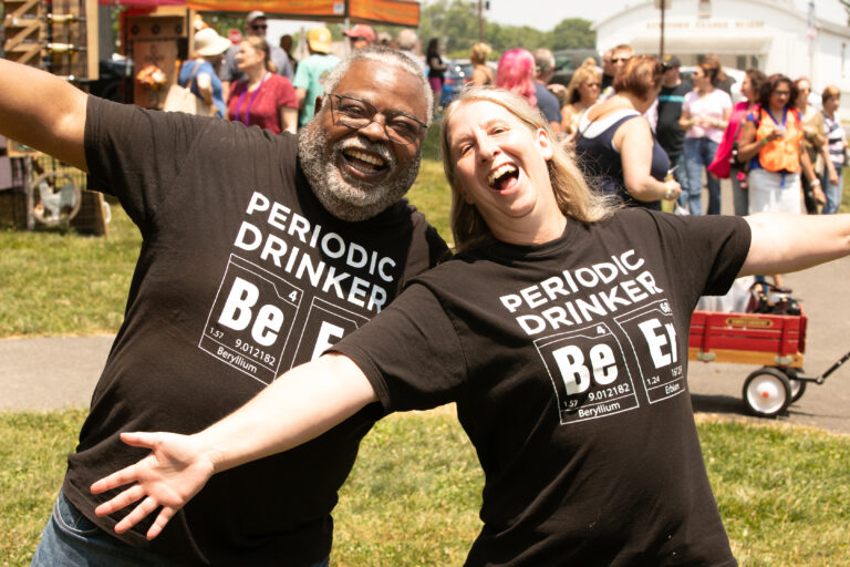 couple posing with arms spread at an outdoor wine festival